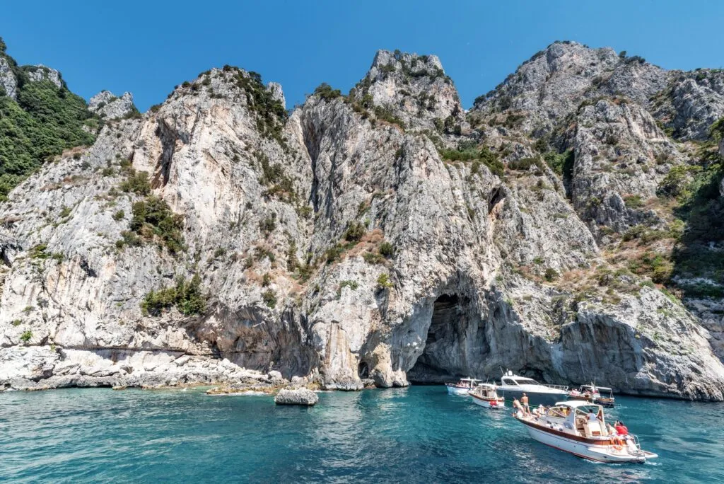 skaliste wybrzeże Capri z grotą i statkiem wycieczkowym