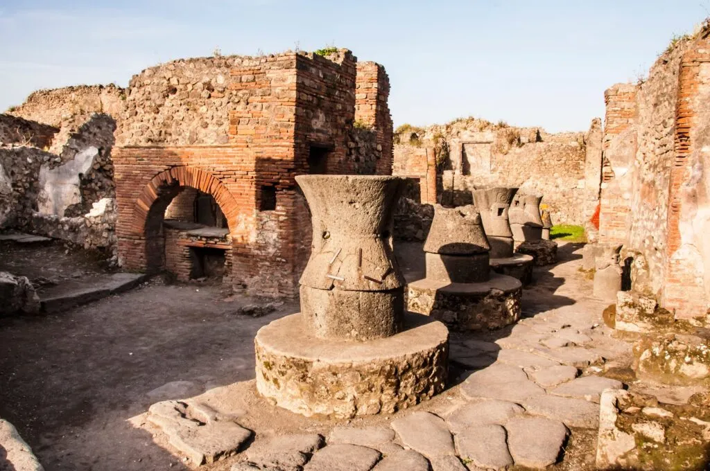 kamienne żarna i piec chlebowy w antycznej piekarni w Pompejach